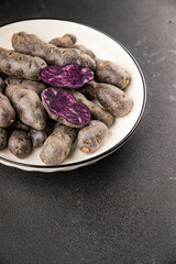 Purple potatoes raw fruit blue potatoe vegetable dish fresh gourmet food background on the table rustic food top view copy space keto and paleo diet vegan and vegetarian food