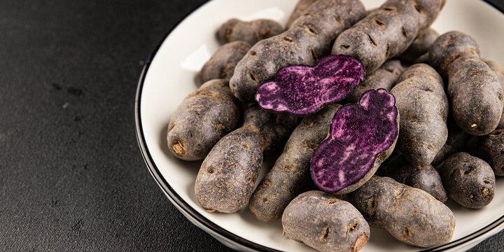 Purple potatoes raw fruit blue potatoe vegetable dish fresh gourmet food background on the table rustic food top view copy space keto and paleo diet vegan and vegetarian food
