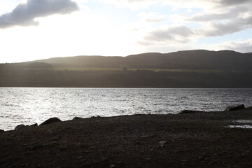 Scottish mountain loch in autumn surrounded by mountain peaks and rugged slopes, with water reflecting the dramatic highland landscape in Scotland