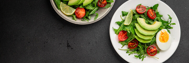 Avocado salad arugula, egg, tomato, mixed greens, vegetables dish fresh delicious gourmet food background tabletop rustic food top view copy space keto and paleo diet vegetarian food