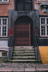 Architectural detail of an aged brick facade and secured, arched entrance
