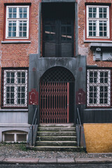 Old stone steps leading to an arched doorway with a red security gate in Hamburg