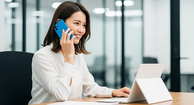 Professional asian businesswoman smiles while handling phone call and typing on laptop