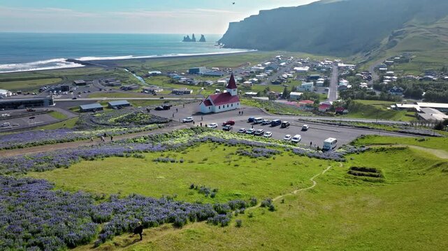 Aerial of Vik I Myrdal harbour and Víkurkirkja church, Iceland. Scenic town with black-sand beach coastline.