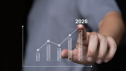 Hand pointing at a rising bar chart marked 2026, business growth, financial forecasting, strategic planning, and future performance analysis for long-term success and organizational development.