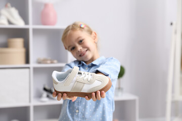 Little girl with one sneaker shoe at shop, selective focus