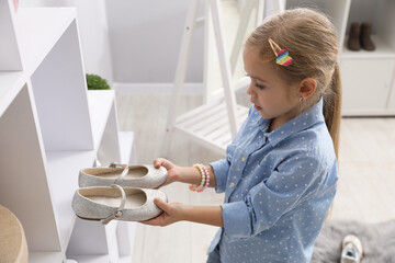 Little girl with pair of beautiful shoes at shop