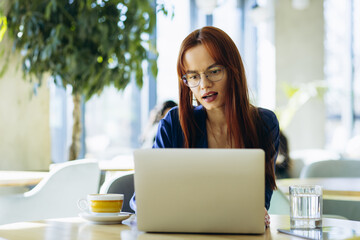Young business woman sitting in a cafe and working on her laptop
