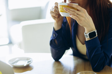 Young business woman sitting in a cafe and working on her laptop and drinking coffee