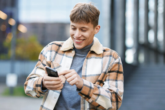 Smiling man in shirt with smartphone on city street
