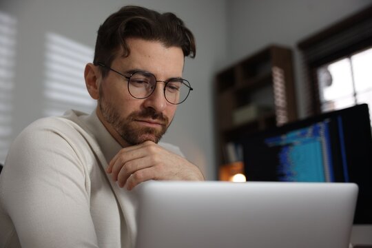 Programmer in glasses working on laptop in office, closeup