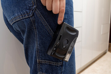 A compact analog camera clipped to the side pocket of blue jeans, showing a practical and stylish way to carry vintage photography gear during everyday movement in a home interior.