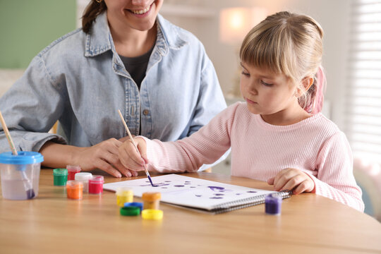Mother and her little daughter drawing together at wooden table indoors, closeup - Powered by Adobe