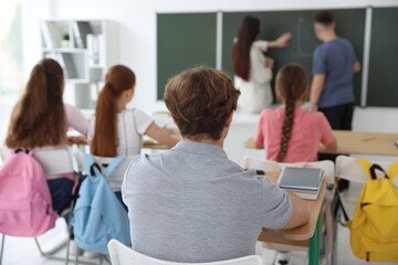 Teacher and students during lesson in classroom, selective focus