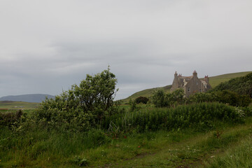 Abandoned ancient stone house in the wild Scottish Highlands, a remote ruined building surrounded by rugged moors, green fields, misty atmospheric landscape and dramatic overcast skies  rural Scotland © faestock