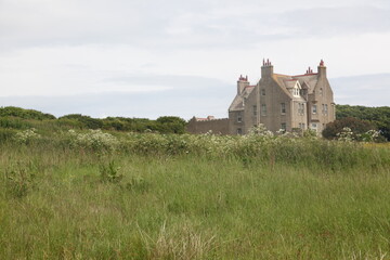Abandoned ancient stone house in the wild Scottish Highlands, a remote ruined building surrounded by rugged moors, green fields, misty atmospheric landscape and dramatic overcast skies  rural Scotland