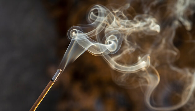 Incense stick burning with wisps of smoke curling upwards. - Powered by Adobe