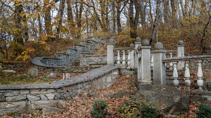 An old staircase in a park covered with yellow maple leaves. Autumn concept.