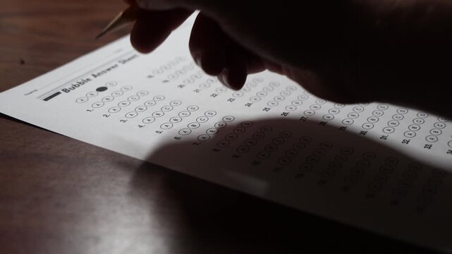 using a pencil to fill in the answers on a multiple choice test sheet, school testing