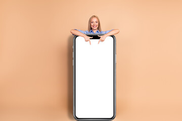 Smiling woman in business attire pointing at blank banner in beige background