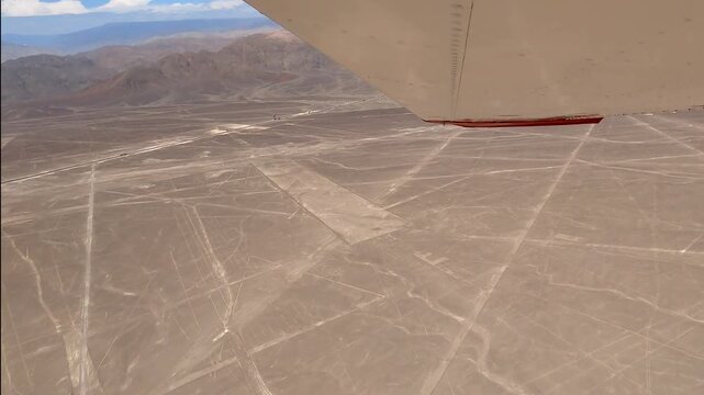 An airplane banks and circles while providing a unique aerial view of the Nazca Lines Spider geoglyph, an ancient design etched into the arid desert floor in Peru, South America