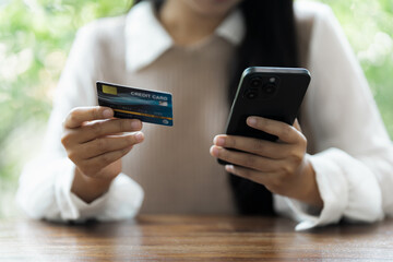 Young woman using credit card with mobile phone to complete purchase through secure online platform