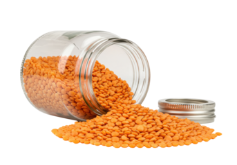 Isolated Red lentils spilling out of an open glass jar alongside its stainless steel lid