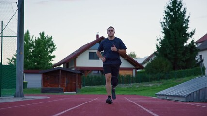 Sports activities on a track, an amputee male athlete using an orthopedic mobility aid, a running blade prosthesis during training, front view. - Powered by Adobe