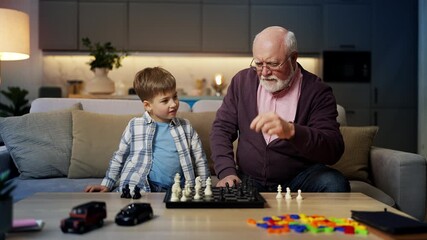 Happy little boy playing chess with grandpa, improving memory and skills - Powered by Adobe