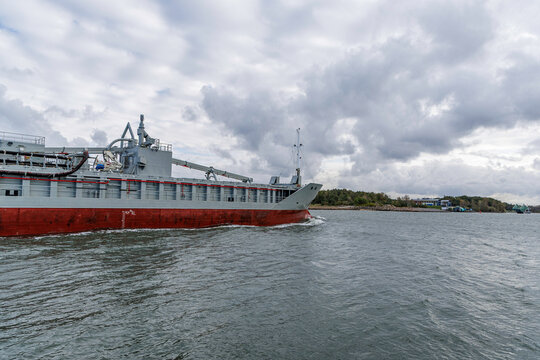 Ship's Side View Navigating Coastal Channel on Overcast Day