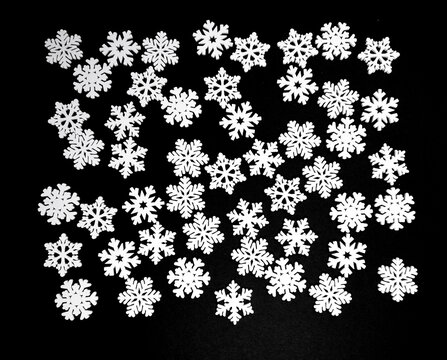 A background of numerous white decorative snowflakes arranged on a black background. Winter holiday composition.