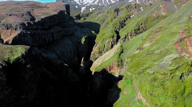 Aerial view of mountain ridge above Mulagljufur Canyon. Drone shot showing rugged peaks, deep valleys, and distant snowfields in the Icelandic highlands.