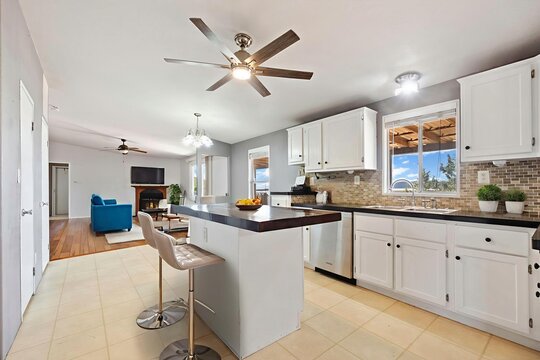 A kitchen with white cabinets, black countertops, and a ceiling fan