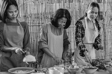 Happy asian mother and daughters preparing fresh traditional papaya salad at house terrace - Thai culture and family concept - Black and white editing