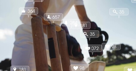 Reaching cricketer in white uniform touching stumps with glove on grassy pitch, social overlay