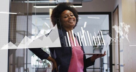 Analyzing analyst in dark blazer pink blouse in office hallway, holding slim laptop with AR charts