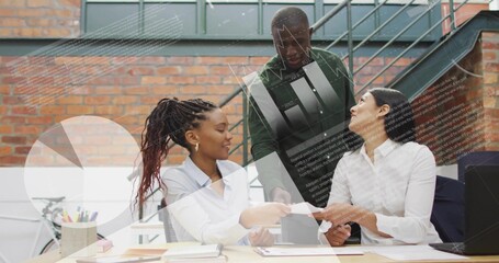 Reviewing colleagues in business attire leaning over wood table in brick office with laptop, papers