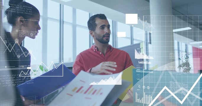 Gesturing man in red shirt discussing printed charts at office table, woman holding blue folder