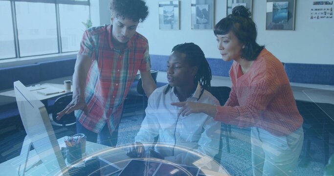 Working team around seated man wearing white shirt operating computer in office, holographic UI