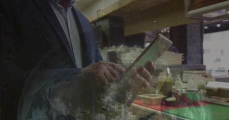 Tapping businessman wearing suit jacket using tablet at cafe counter, with condiments, copy space