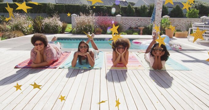 Lying four women sunbathing in swimwear and sunglasses on backyard pool deck with colorful towels
