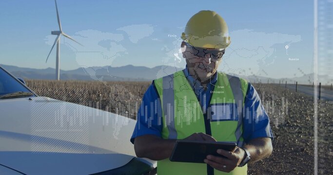 Holding tablet technician in yellow hardhat hivis vest monitoring at wind farm near white vehicle - Powered by Adobe