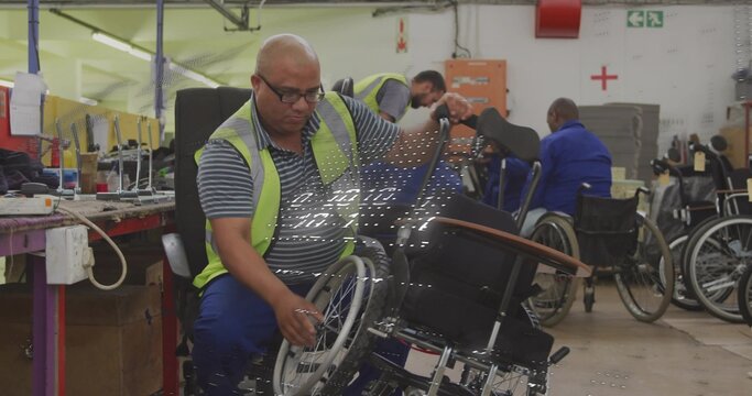 Working technician adjusting wheelchair wheel at workshop, wearing hi-vis vest and striped polo