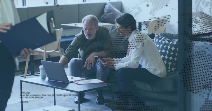 Discussing two seated men in white shirt pointing at laptop on lounge sofa, with clipboard