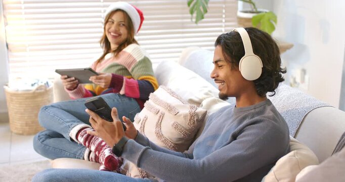 Couple wearing Santa hat spotting holiday clip scrolling smartphone sharing it bringing joy at home