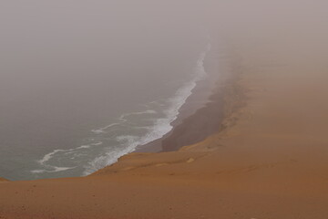 The Pacific Ocean's craggy sandstone cliffs are shrouded in fog in Paracas National Park.