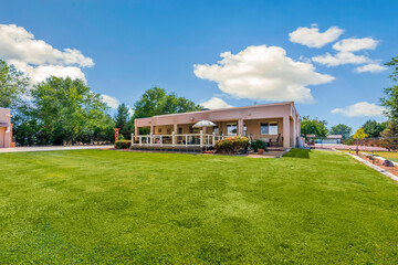 Obraz premium Charming Residential Home Surrounded by Lush Greenery and Blue Skies