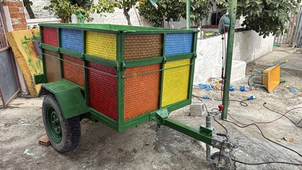 Vibrant multicolored trailer with green frame parked in rustic yard