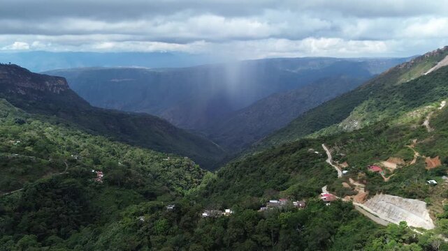 Aerial shot of rain falling from a cloud in the middle of mountains