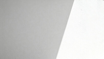 Close-up of two textured surfaces meeting at a diagonal angle, one light gray and one white.